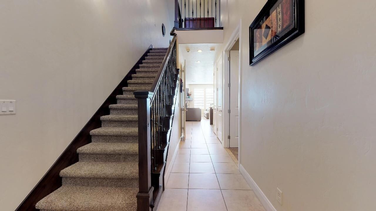 A staircase with carpeted steps and a handrail, leading to an upper floor.