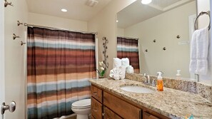 A bathroom with a striped shower curtain, a sink with a soap dispenser, and a mirror. - Canyon Oasis 4 Bedroom Apts by RedAwning (Washington)