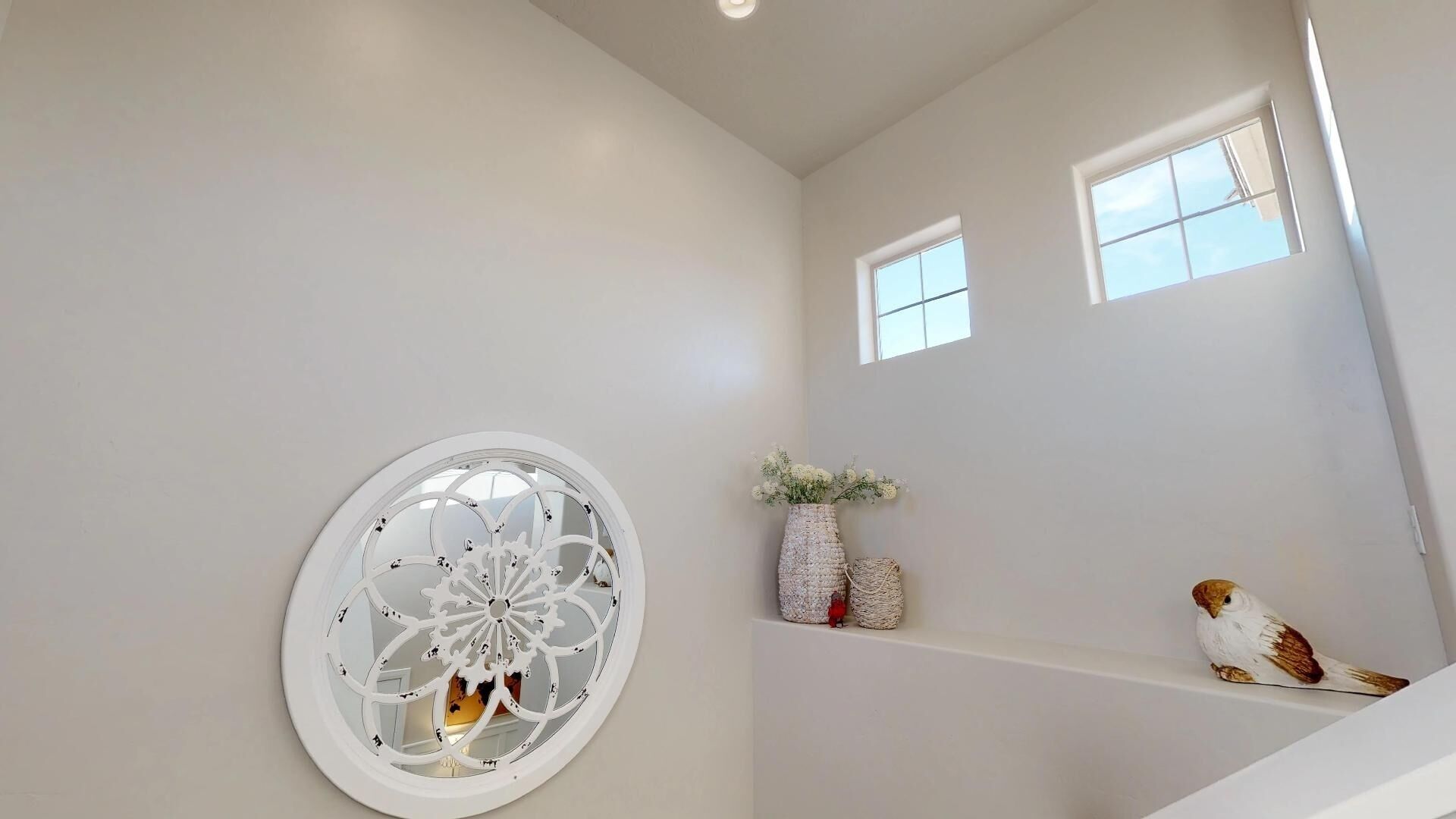 A staircase with a white railing, a decorative wall piece, and a small bird figurine.