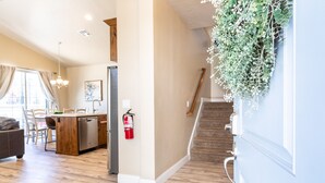A modern kitchen with wooden flooring, a dining area with chairs, a kitchen island, and a staircase with a plant hanging from the wall. - Poolside 3 Bedroom Apts by RedAwning (Washington)