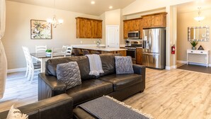 A modern living room with a leather sofa, wooden cabinets, and a kitchen area with stainless steel appliances. - Poolside 3 Bedroom Apts by RedAwning (Washington)
