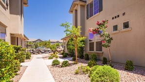 A residential building with a paved pathway, small shrubs, and a tree with pink flowers. - Poolside 3 Bedroom Apts by RedAwning (Washington)