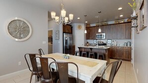 A modern kitchen with dark wood cabinets, stainless steel appliances, and a white dining area with a chandelier. - Southern Comfort 3 Bedroom Apts by RedAwning (Washington)