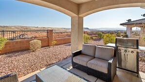 Eine überdachte Terrasse mit Grill, Sitzgelegenheit und Blick auf eine Wüstenlandschaft.