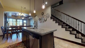 A kitchen with a granite island, a dining area with a chandelier, and a staircase with a banister. - Kolob 3 Bedroom Apts by RedAwning (Washington)