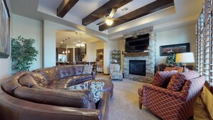 A spacious living room with a leather sectional sofa, patterned armchairs, a stone fireplace, and a large flat-screen TV mounted above it. - Kolob 3 Bedroom Apts by RedAwning (Washington)