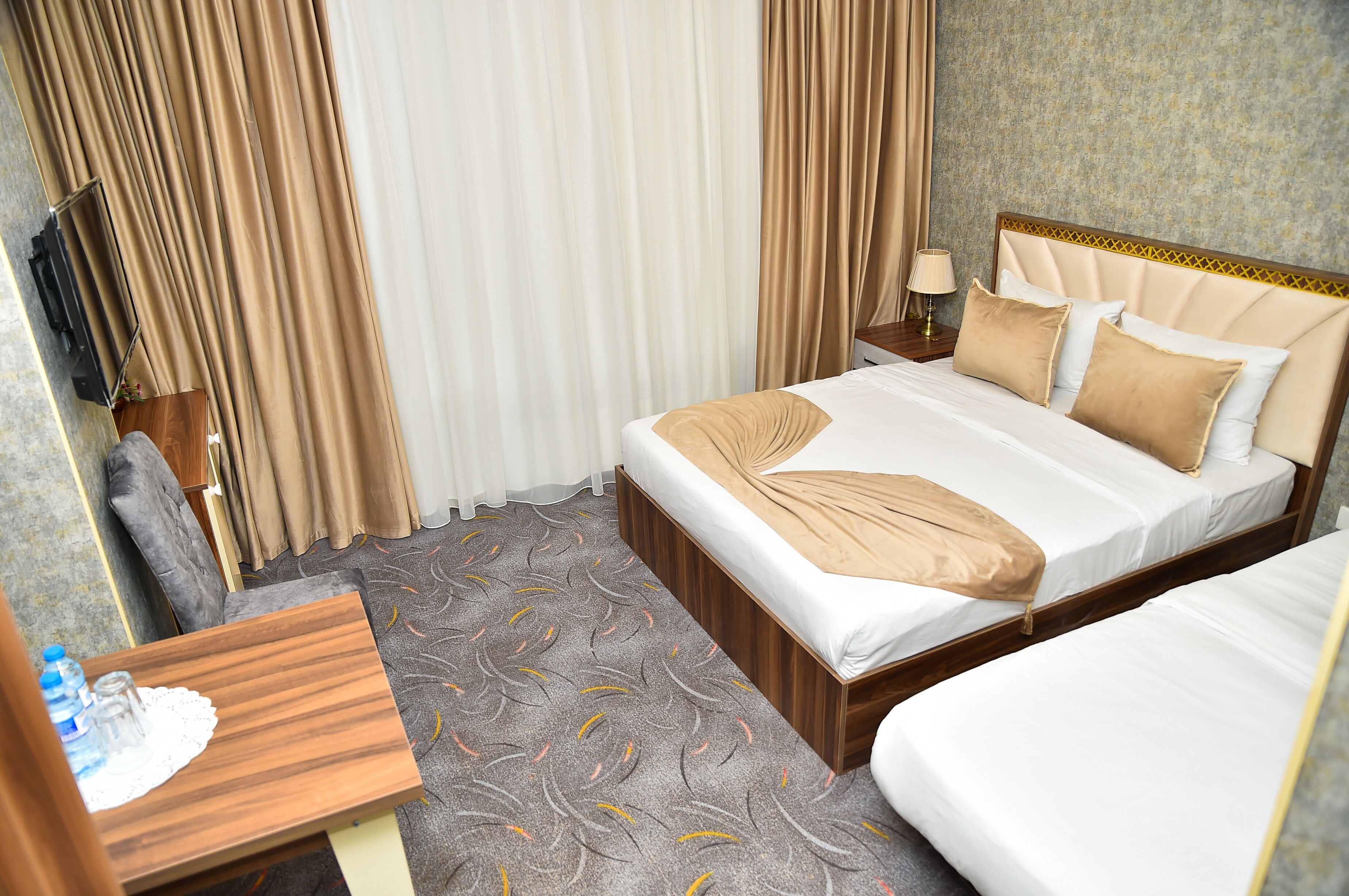 A hotel room with a bed, bedside table, lamp, and curtains.