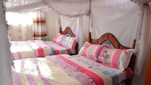 A bedroom with two single beds, each with a canopy. - Tollview Classic Hotel (Ruiru)