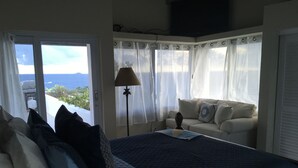 Una camera da letto con un letto, un divano, una lampada e vista sull'oceano.