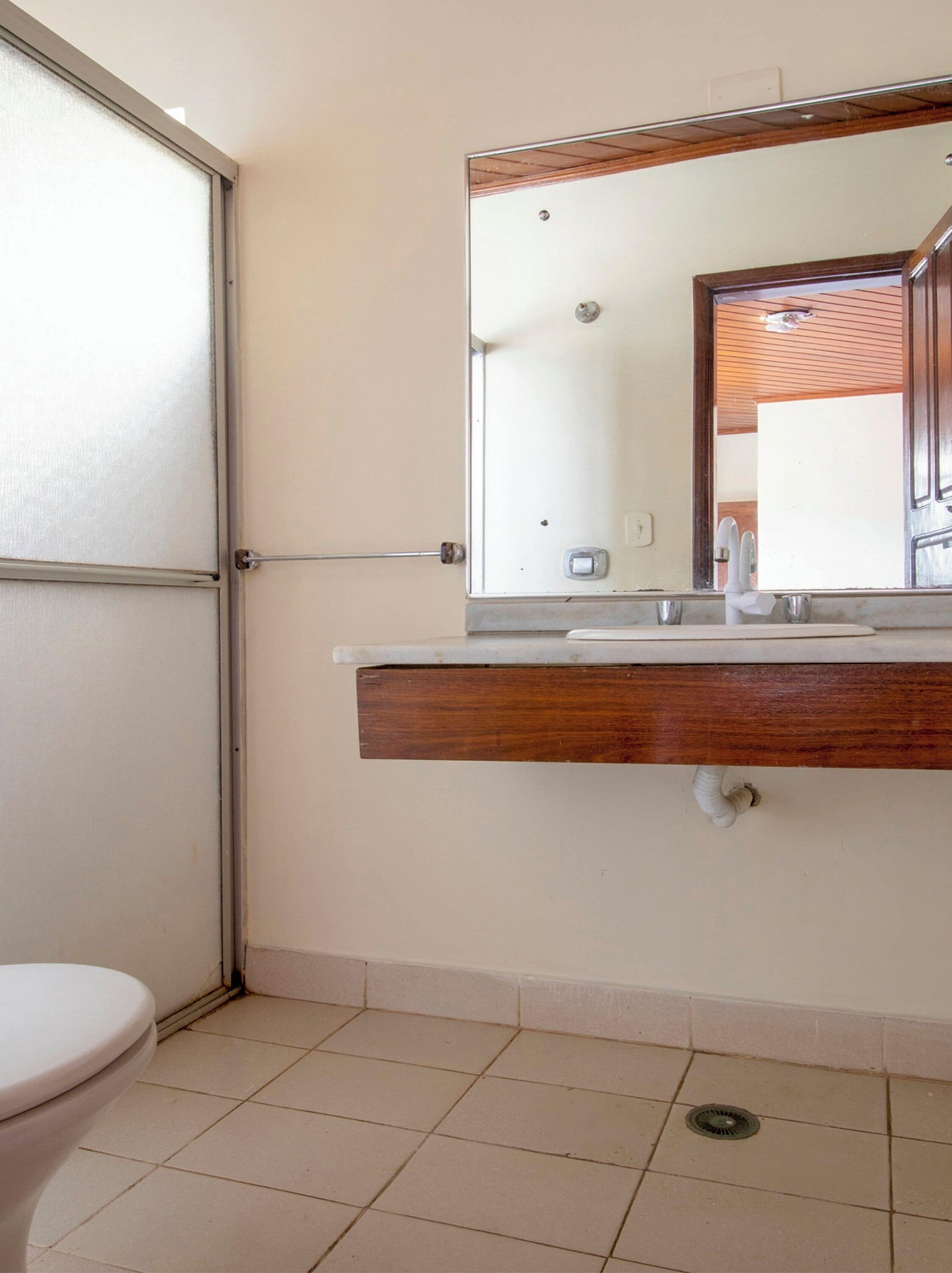 A bathroom with a toilet, a sink with a mirror, and a shower door.