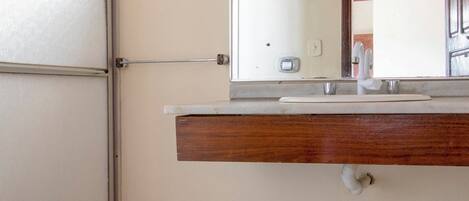 Un baño con inodoro, lavamanos con espejo y mampara de ducha.