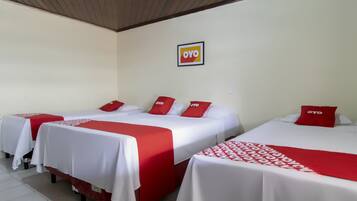 Une chambre d’hôtel avec trois lits, chacun doté de draps rouges et blancs, et un logo sur le mur.