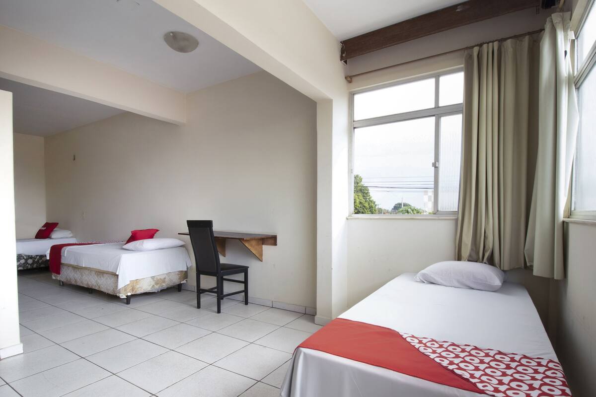 A hotel room with two beds, a desk, and a window with curtains.