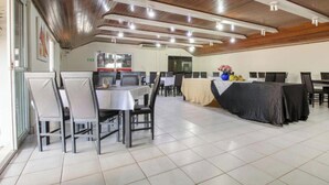 A dining area with tables and chairs, a kitchen in the background, and a wooden ceiling. - OYO New Anápolis Hotel, Imperatriz (Imperatriz)