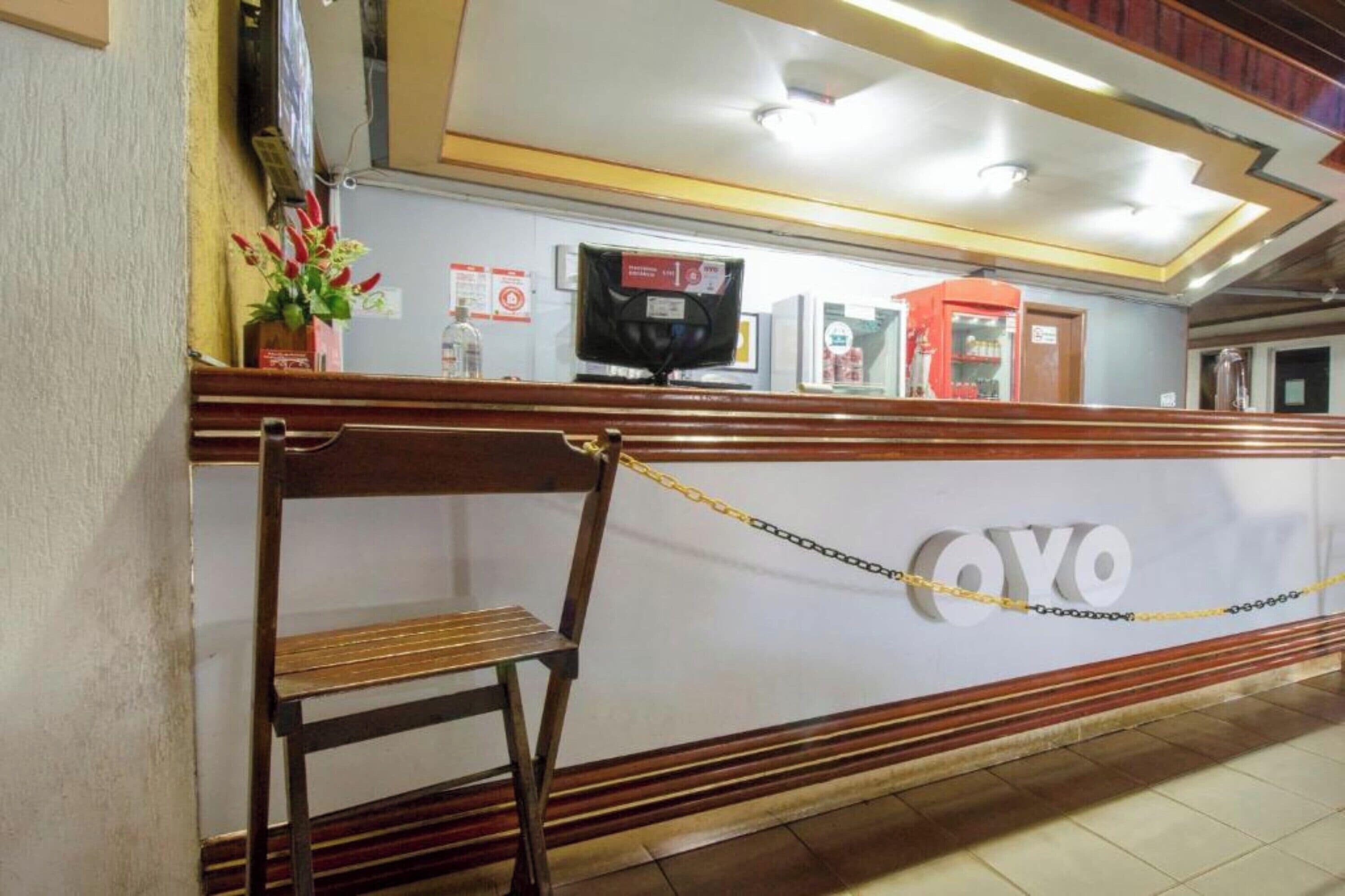 A reception desk with a chain barrier, a television, and a sign with the name 'OYO'.