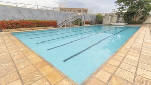 A swimming pool with tiled edges and a stone deck surrounding it. - OYO New Anápolis Hotel, Imperatriz (Imperatriz)