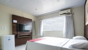 A hotel room with a bed, a television, a mini-fridge, and a window with curtains. - OYO New Anápolis Hotel, Imperatriz (Imperatriz)