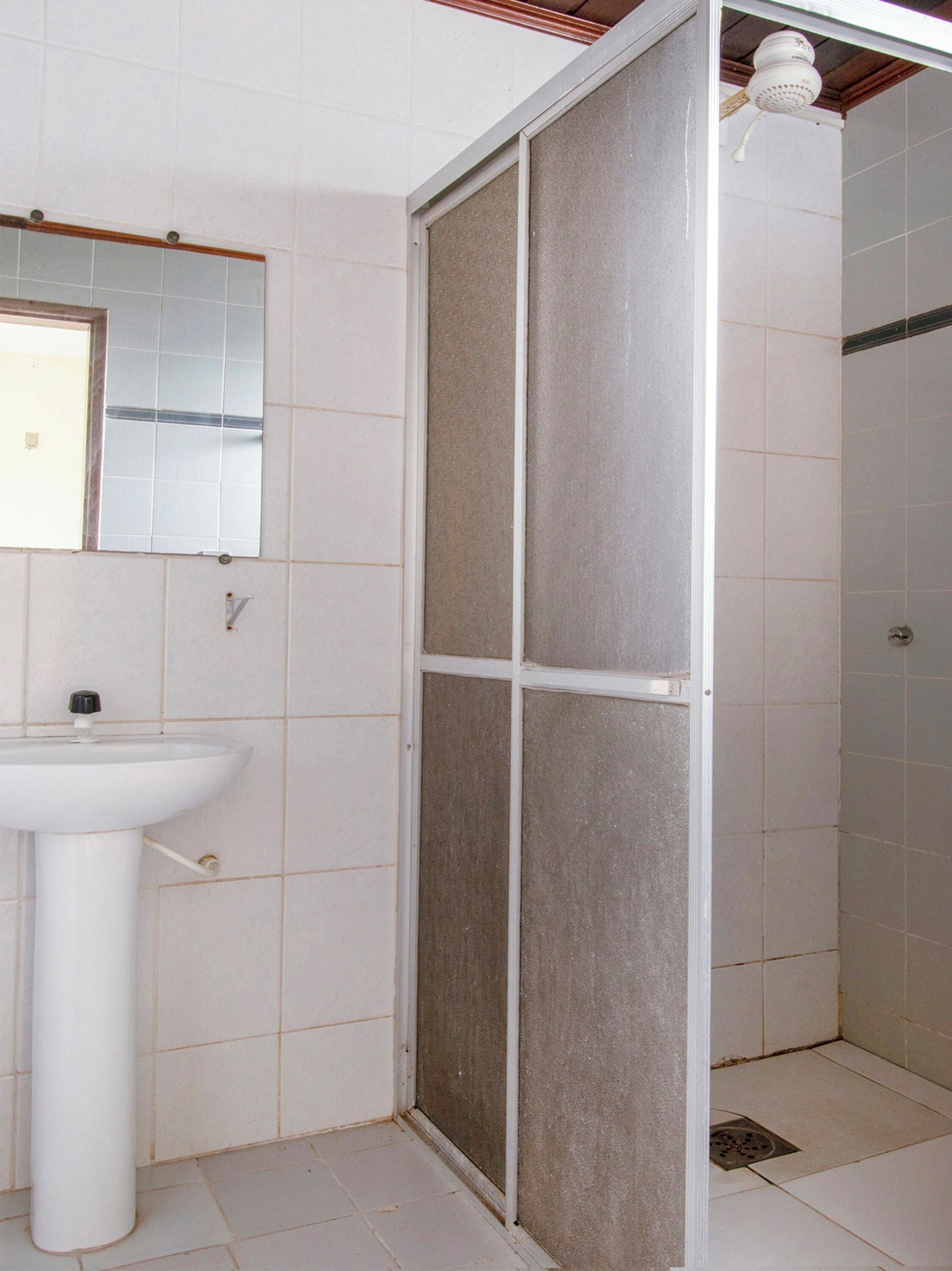 A bathroom with a white sink, a mirror, and a shower with a frosted glass door.