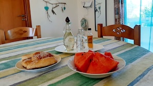 A dining table with plates of food, a striped tablecloth, and various bottles. - Kalamaki Sight Irene's (Faistos)