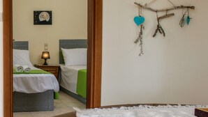 A hotel room with two beds, a painting, and a wall decoration. - Kalamaki Sight Irene's (Faistos)