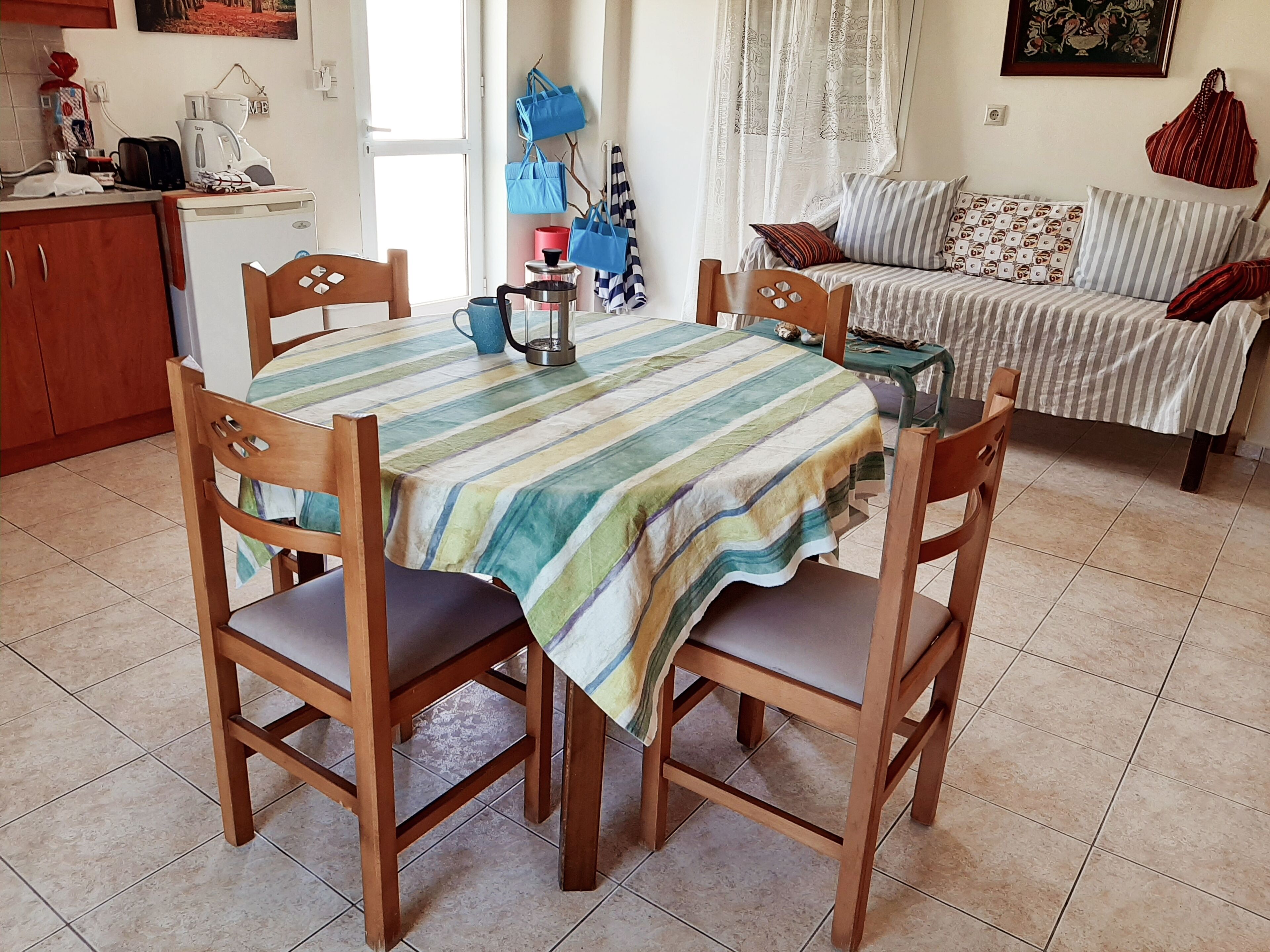A dining area with a striped tablecloth, wooden chairs, and a coffee machine.