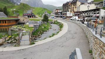 Une ville de montagne traversée par une rivière, avec des murs en pierre et des bâtiments dotés de balcons.