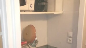 Kompakti keittiö, jossa on mikroaaltouuni, vedenkeitin ja pieni induktioliesi.