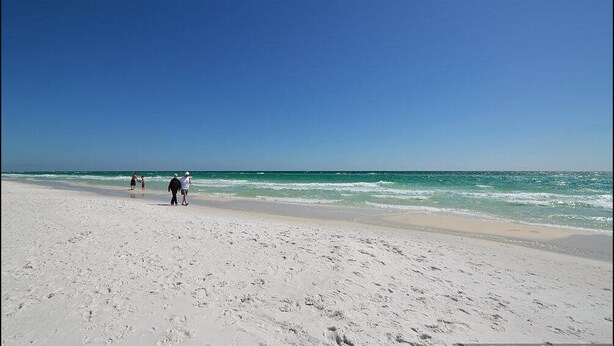 Una playa con arena blanca y agua tranquila.