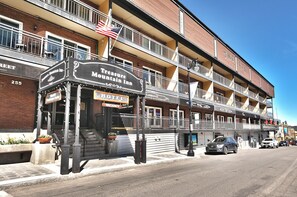 Un edificio de varios pisos con un letrero del Treasure Mountain Inn, que cuenta con un balcón con barandillas y una bandera estadounidense.
