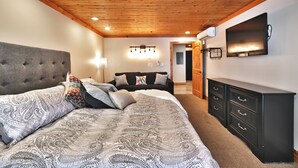 A bedroom with a large bed, a dresser, a television, and a ceiling with wooden beams. - Top of Main Street - TMI with Parking (Park City)