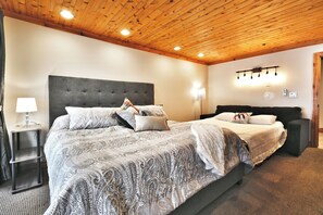 Een slaapkamer met een groot bed, een nachtkastje, een lamp en een plafondarmatuur.