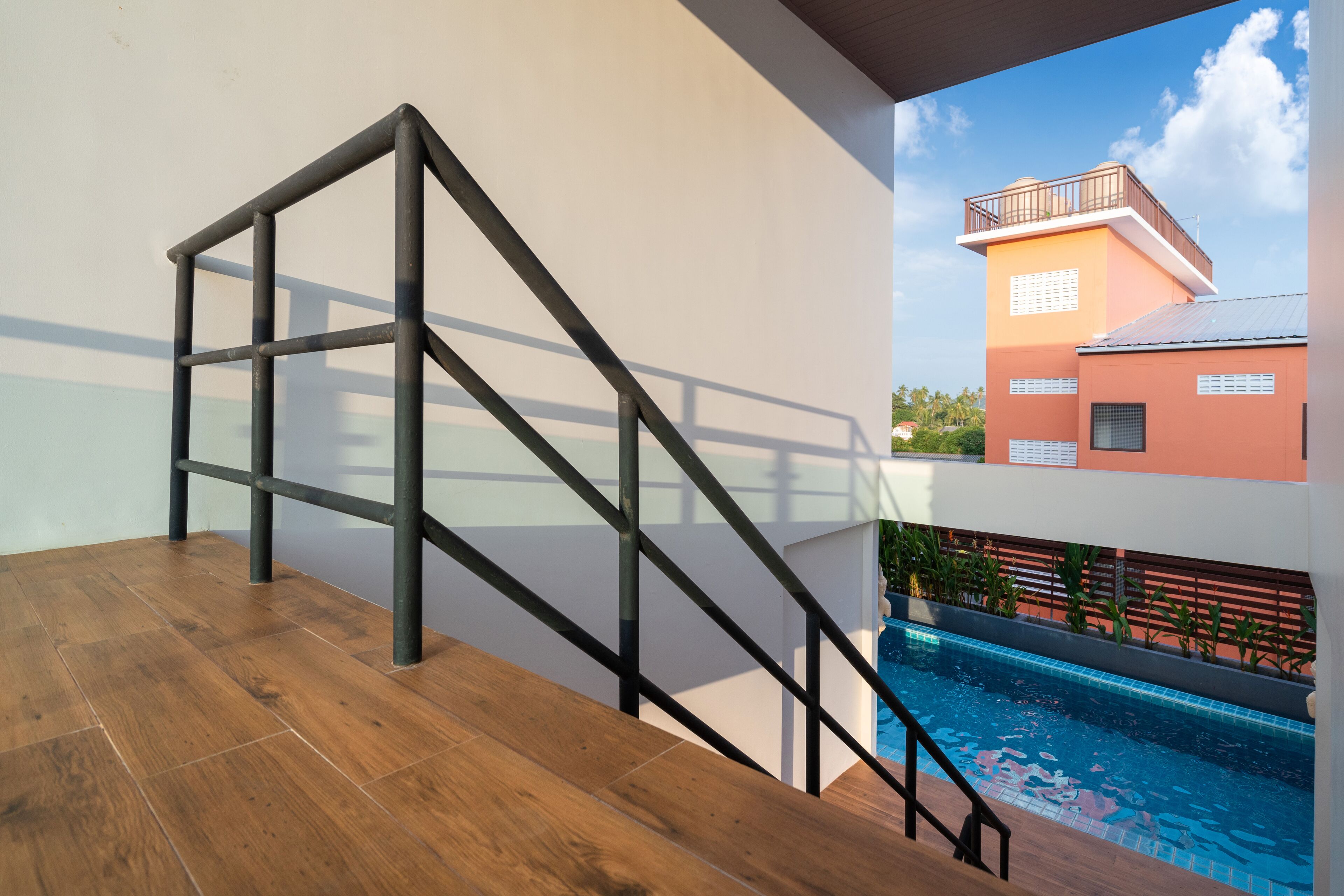 A modern staircase with a glass railing leading to a rooftop area with a pool.