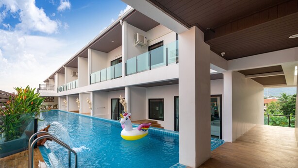 A modern hotel with a rooftop pool, a unicorn float, and a view of the city. - The Thames Pool Access Resort SHA+ (Chalong)