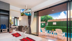 A hotel room with a bed, a desk, a chair, a TV, and a view of an outdoor swimming pool. - The Thames Pool Access Resort SHA+ (Chalong)
