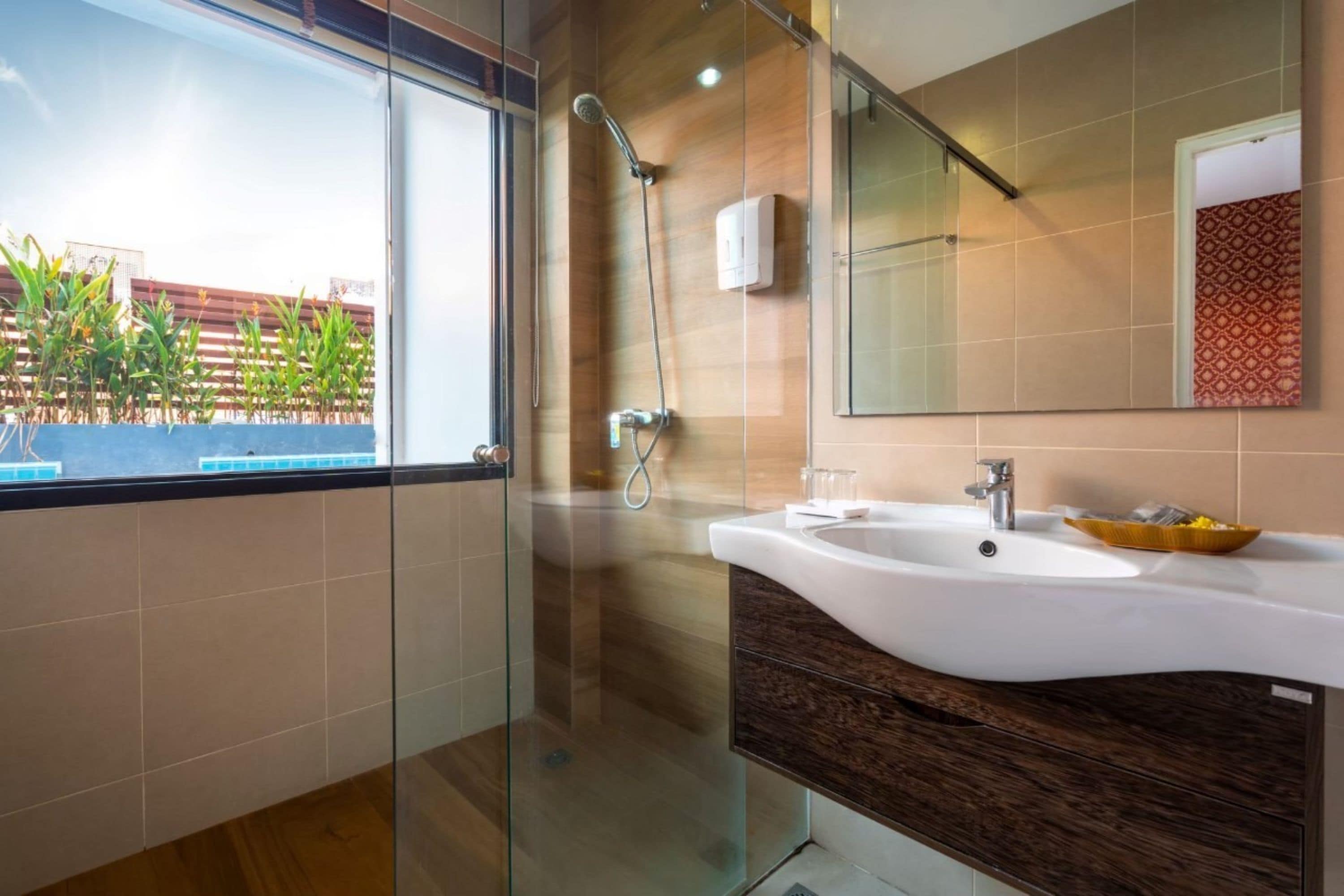 Une salle de bain moderne avec une douche à parois de verre, un lavabo blanc et un grand miroir.