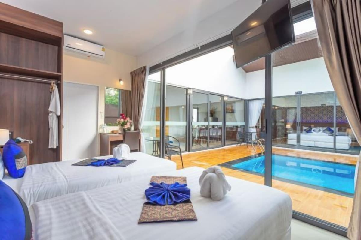 A hotel room with two beds, a large window, and a view of an outdoor swimming pool.