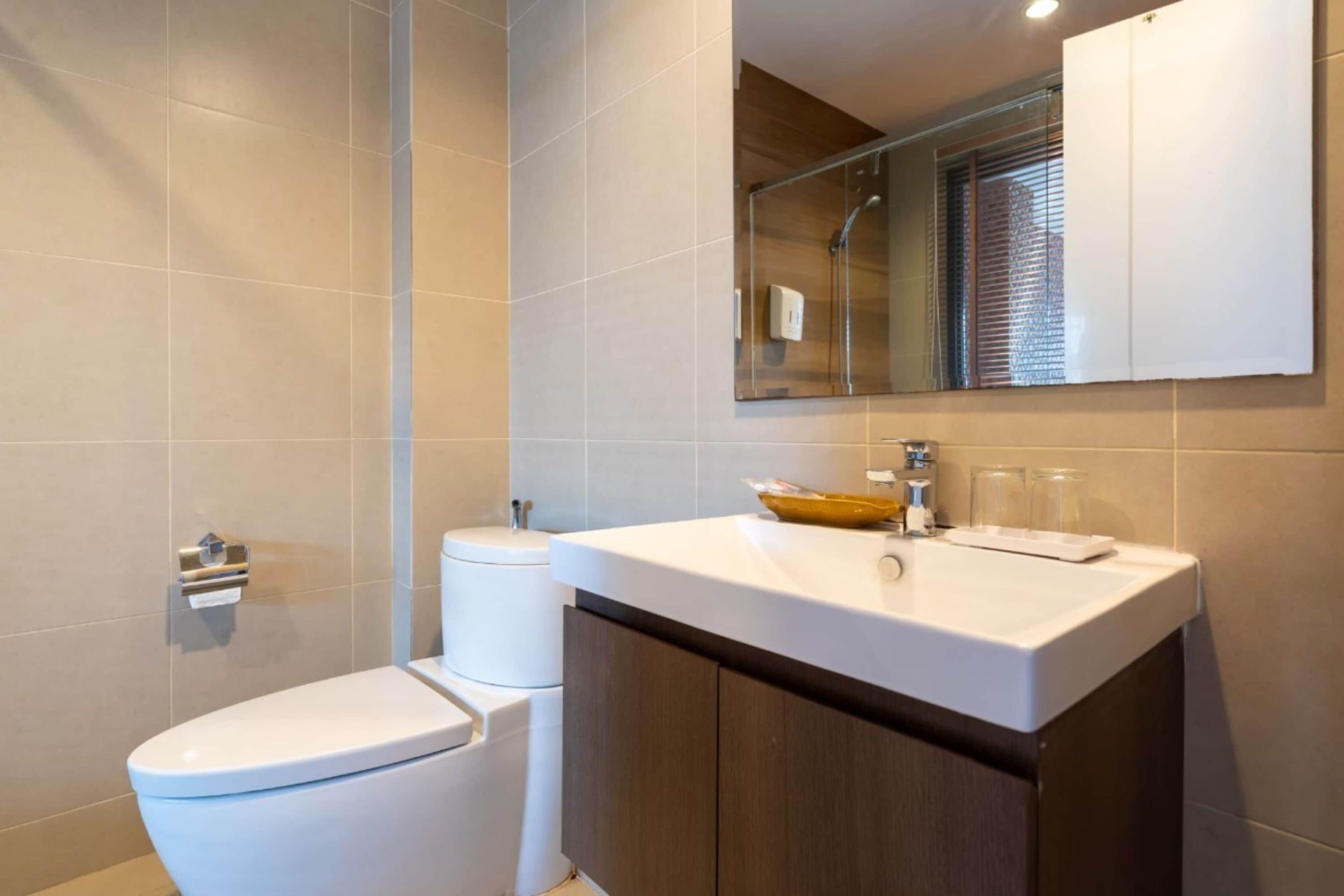 Ein modernes Badezimmer mit Toilette, Waschbecken mit Spiegel darüber und einer Duschkabine.