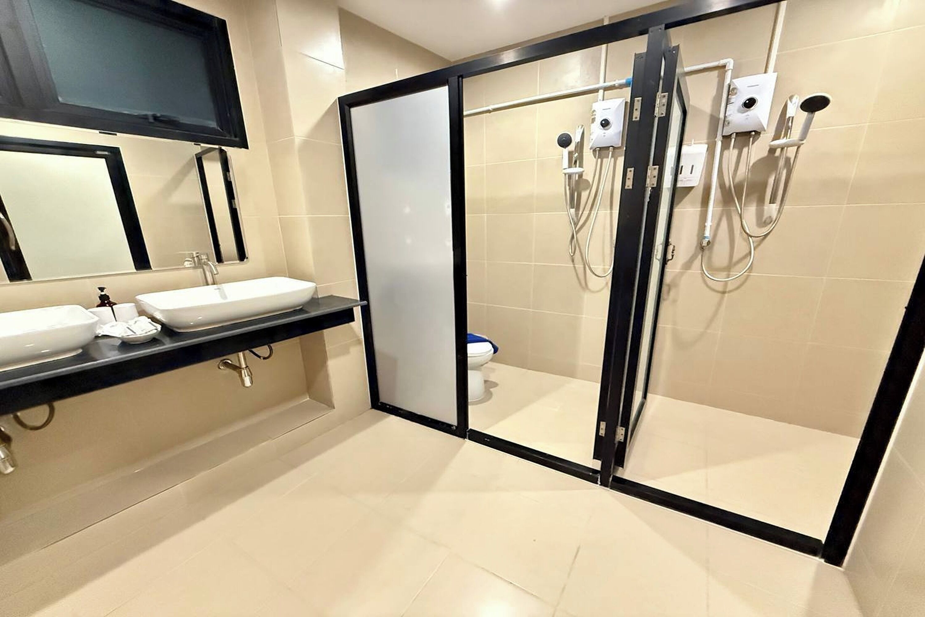 Ein modernes Badezimmer mit einer gläsernen Duschkabine, einem Waschbecken mit Spiegel und einer Toilette.