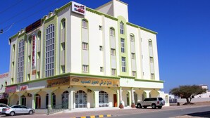 A multi-story building with a green and white facade, featuring a hotel sign and a restaurant sign.