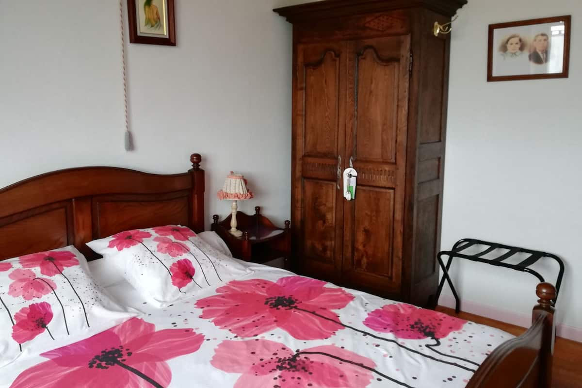 Een slaapkamer met een houten bed, een kledingkast en een metalen rek.