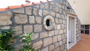 Un muro de piedra con un ventanal circular y una puerta.
