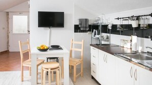 Una cocina moderna con armarios blancos, una zona de comedor con mesa y sillas, un televisor de pantalla plana y un tragaluz.