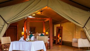 A tented dining area with a table set for two, wooden chairs, and a cozy interior with warm lighting. - Asanja Grumeti (Serengeti)