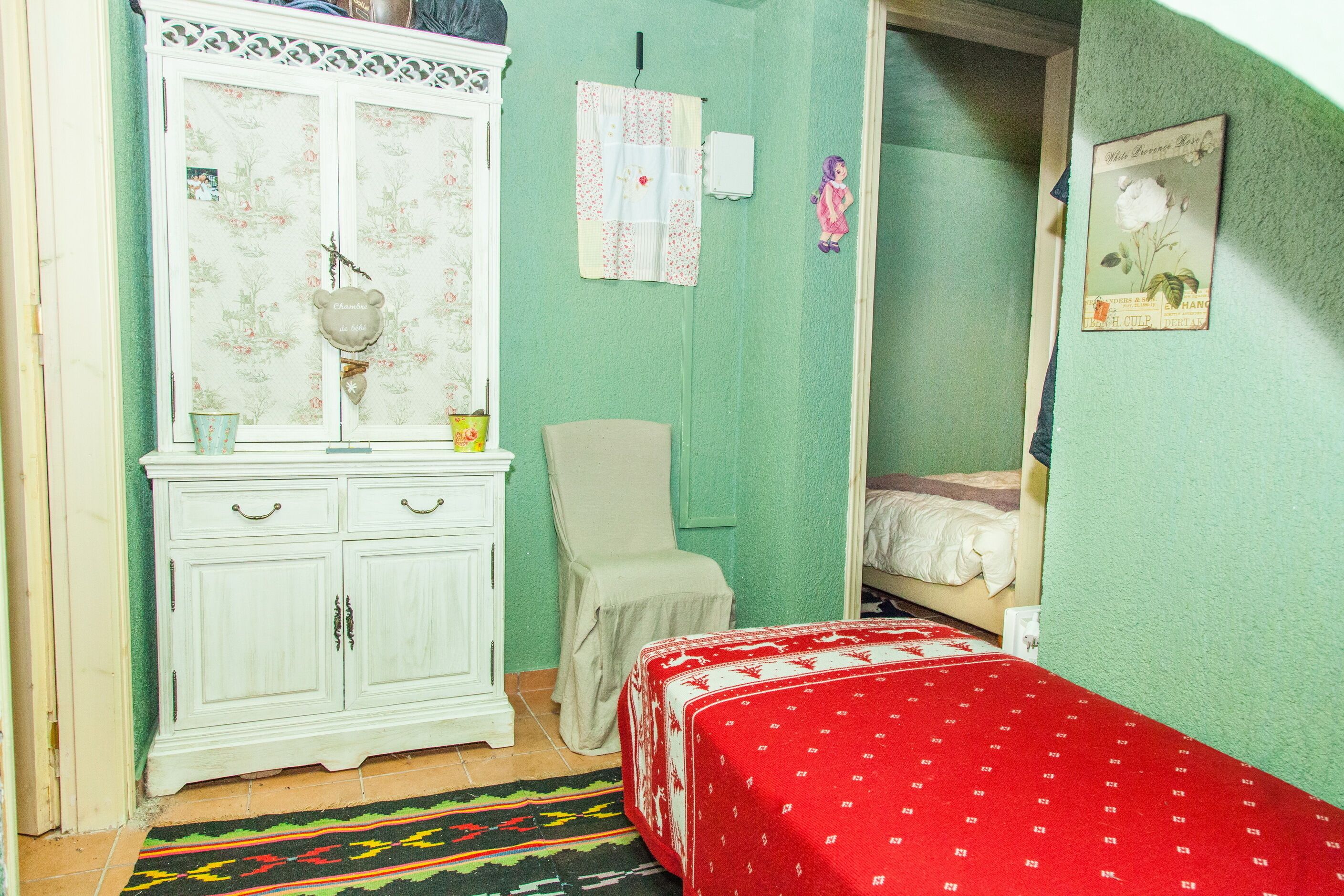 A small, cozy bedroom with a single bed, a white dresser, and a chair.