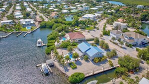 Vista aérea de una zona residencial costera con casas, un muelle y una piscina.