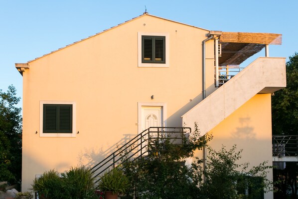 A two-story building with a white facade, a central door, and two windows with shutters. - Apartment Marlo (Dubrovnik)