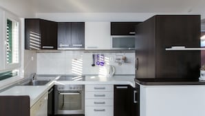 Een moderne keuken met donkere kastjes, een roestvrijstalen spoelbak en een ingebouwde oven.