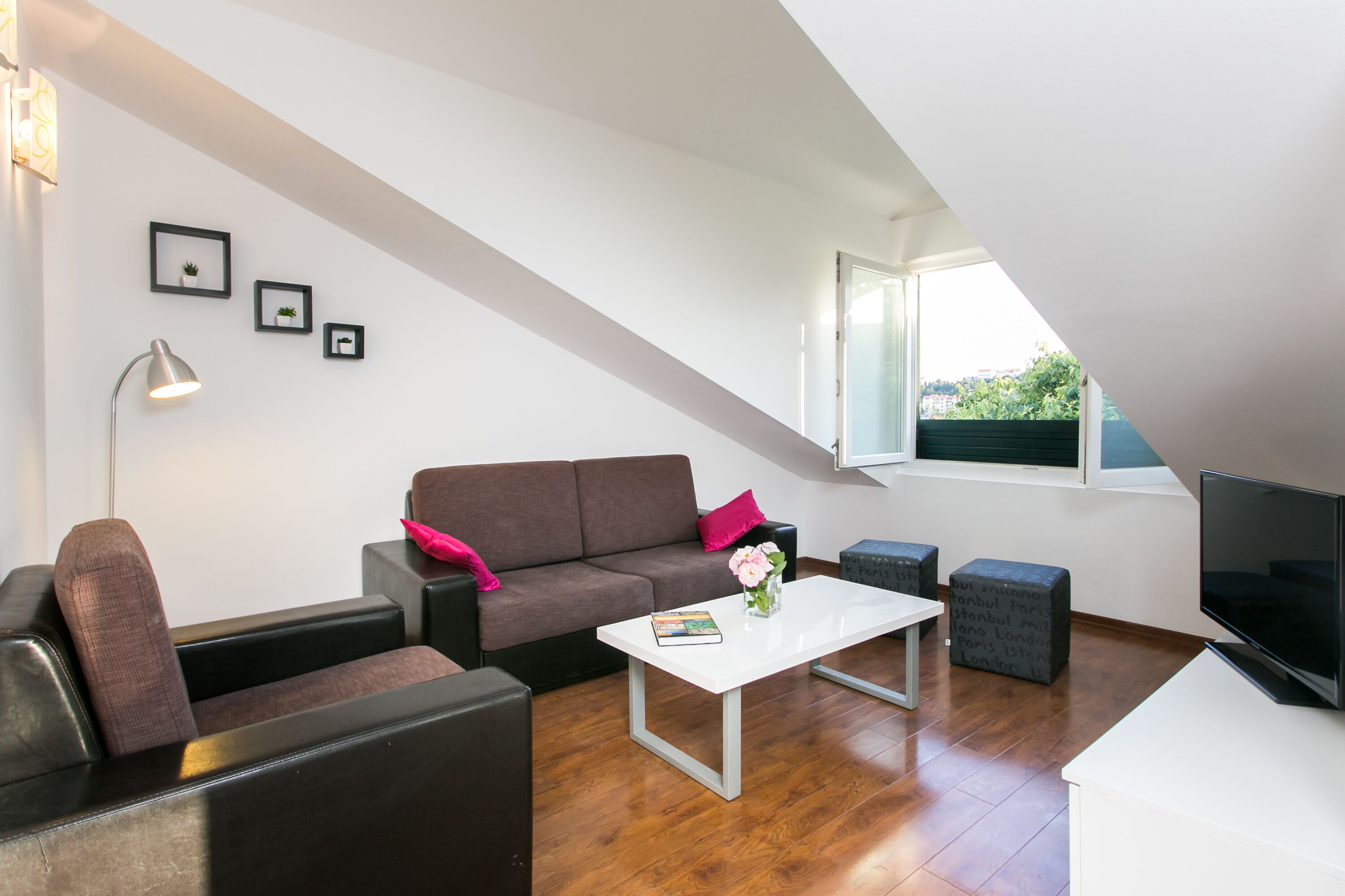 A modern living room with a brown sofa, a white coffee table, and a flat-screen TV.