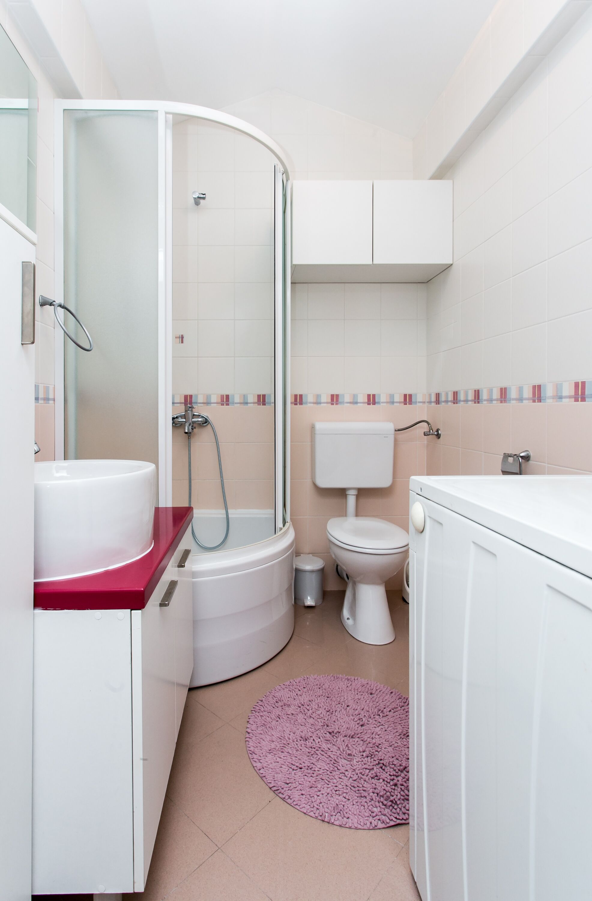 A bathroom with a shower, toilet, sink, and cabinets.