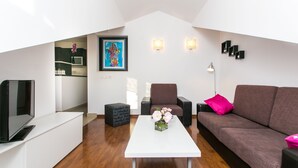 Een moderne woonkamer met een witte salontafel, een bruine bank, een televisie en een schilderij aan de muur.